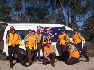 CCC Corpsmembers pose in front of Australian flag and vehicle