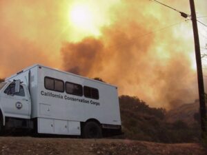 White CCC crew vehicle parked on road with smoke covered sun in background