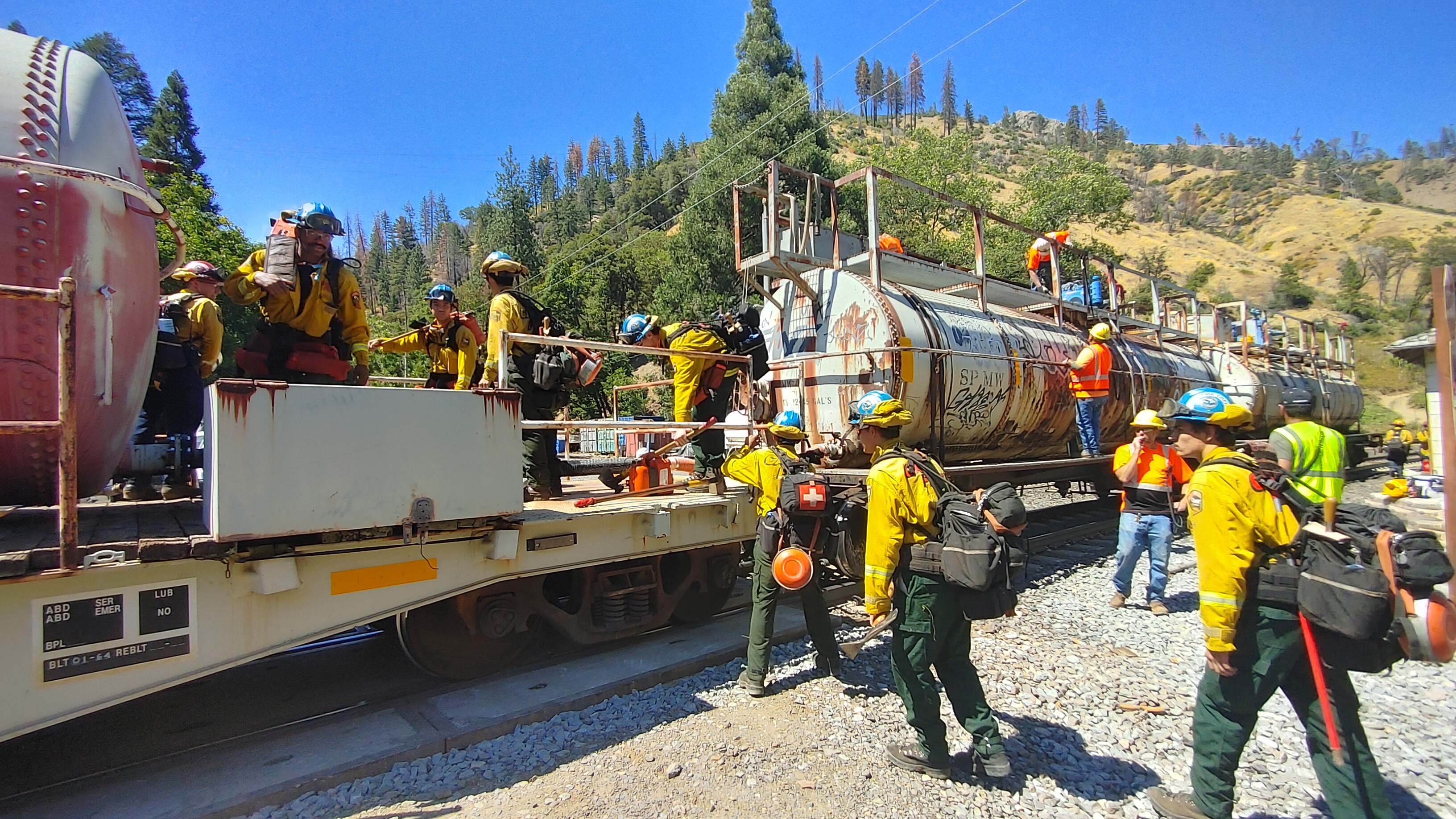 corpsmembers in yellow nomex climb aboard a train