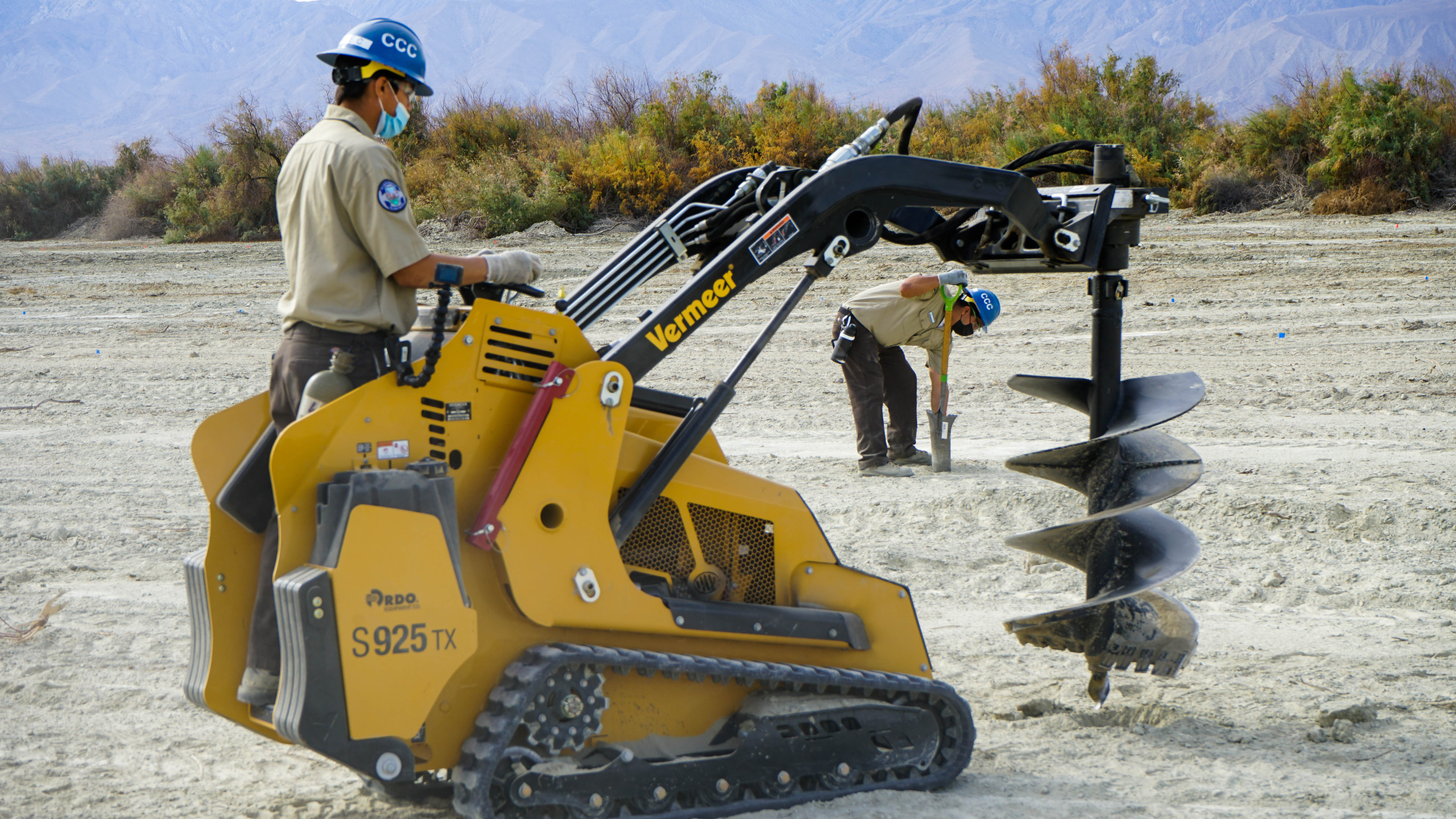 man on skid steer prepares to use auger bit