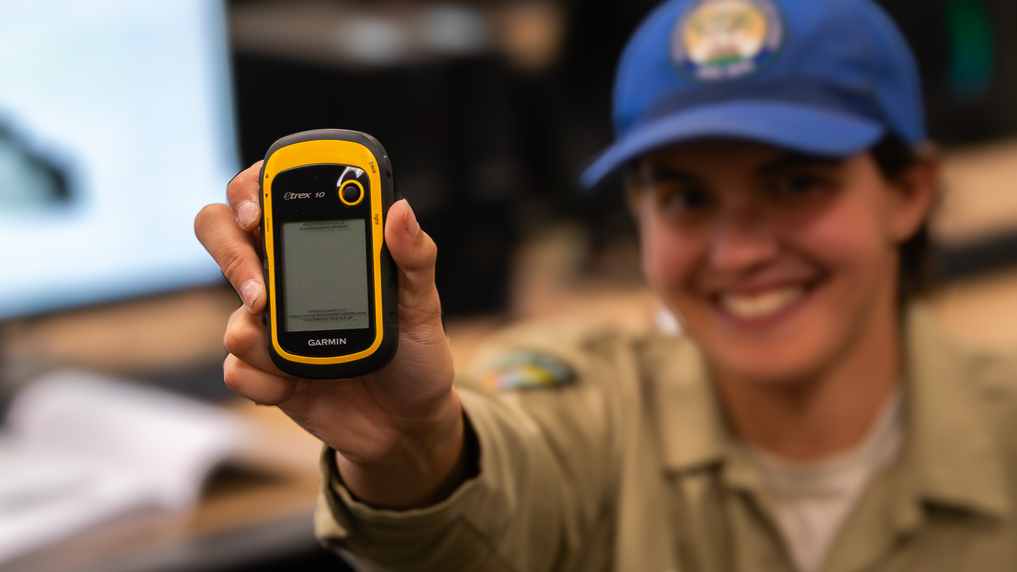 Corpsmember, Sam Sloan, holds up a Garmin. 