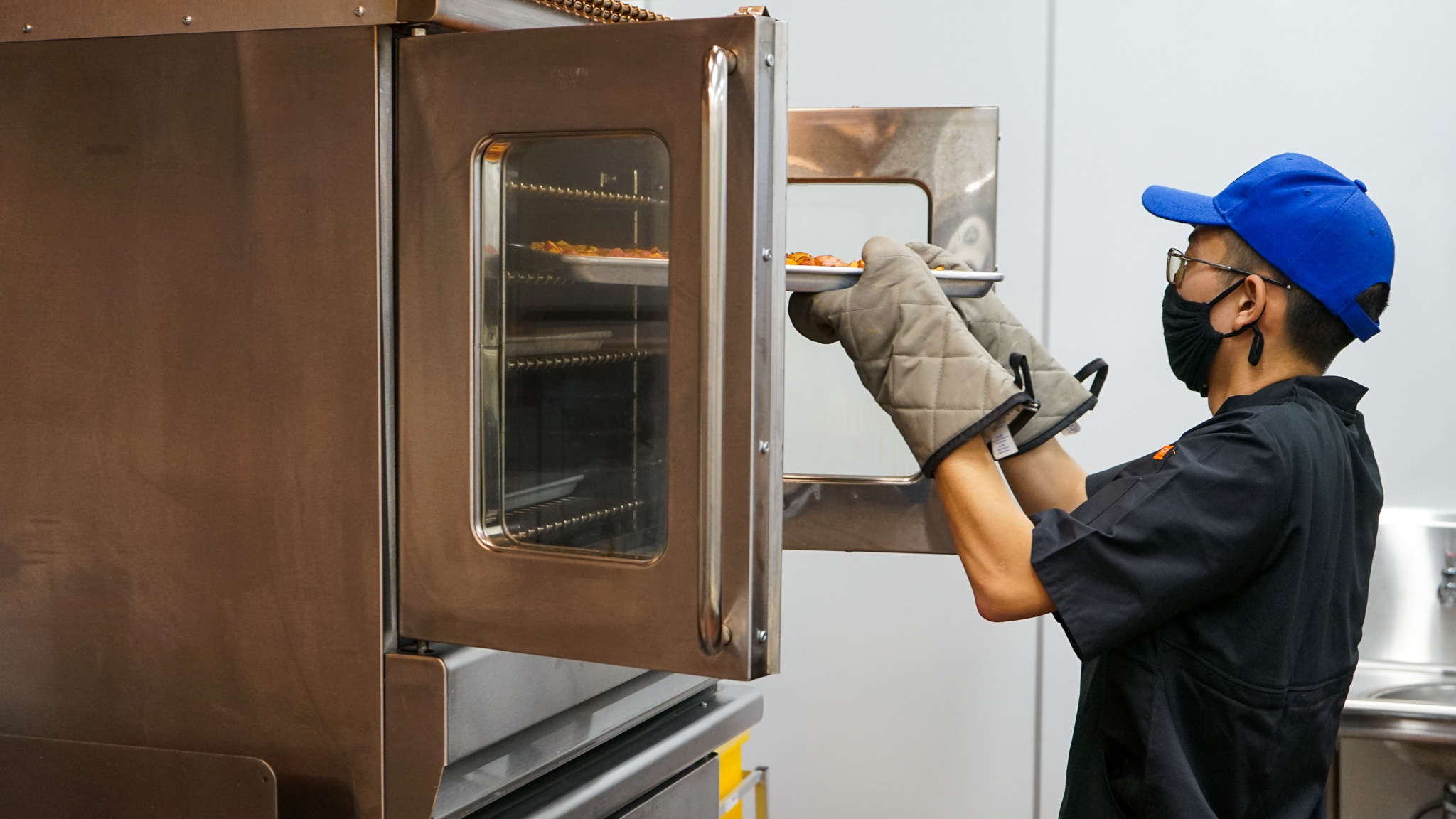 Marcus Kim throws potatoes into an oven while preparing breakfast for Corpsmembers at the Placer Center in early 2022