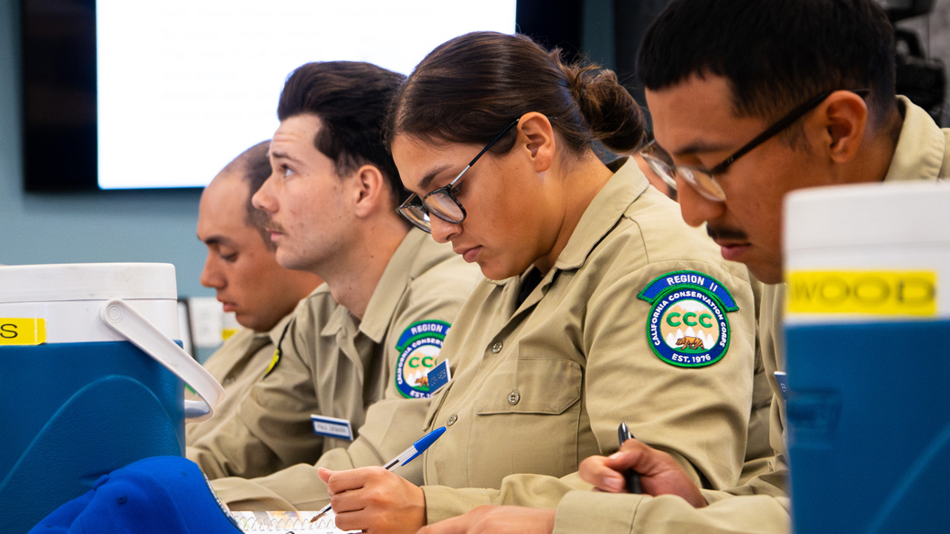 corpsmembers in classroom looking at instructor who is off camera and taking notes