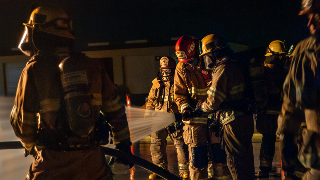 firefighter receives instructions while operating a fire hose nozzle