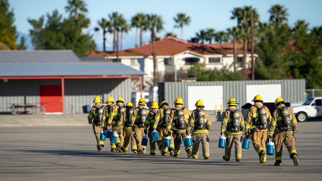 firefighters walking across concrete pavement walking away toward a building