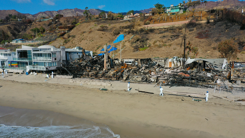 corpsmembers on beach with silt socks in front of burned structures